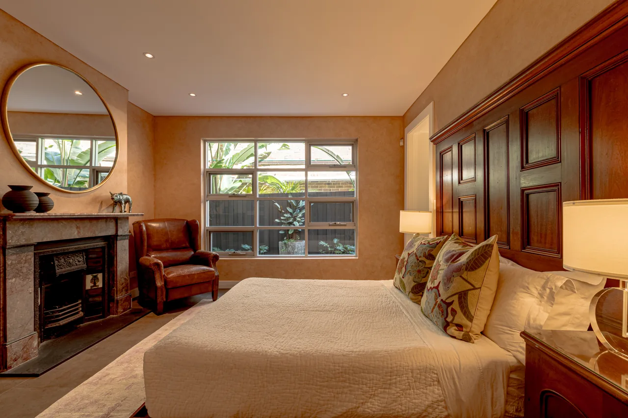 Bedroom with timber furniture and windows overlooking greenery