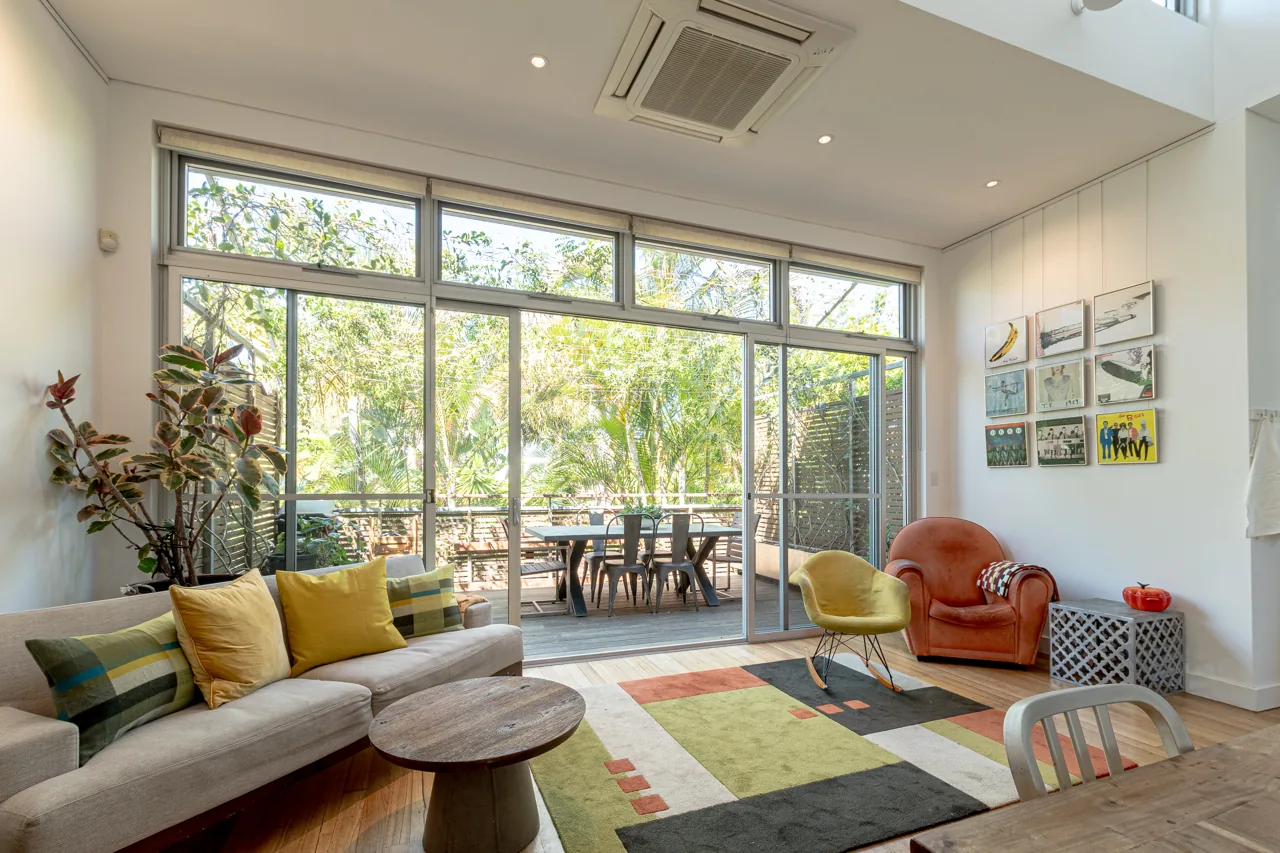 Light-filled living room opening onto a leafy deck in Manly