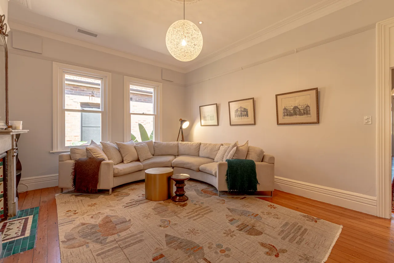 Lounge with curved sofa, timber flooring and framed artwork